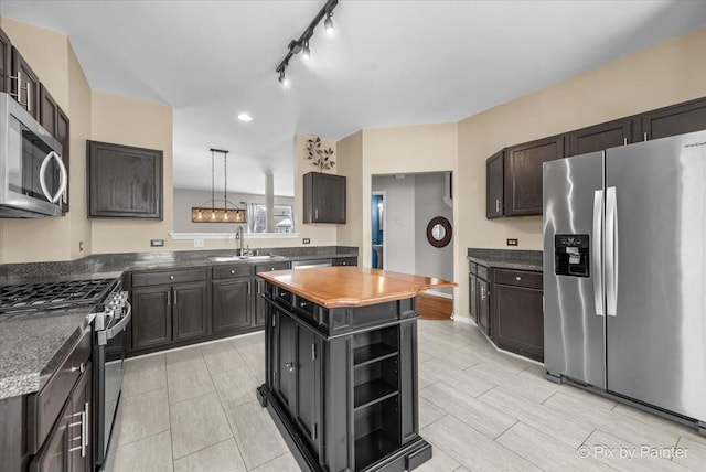 kitchen featuring a kitchen island, open shelves, a sink, stainless steel appliances, and rail lighting