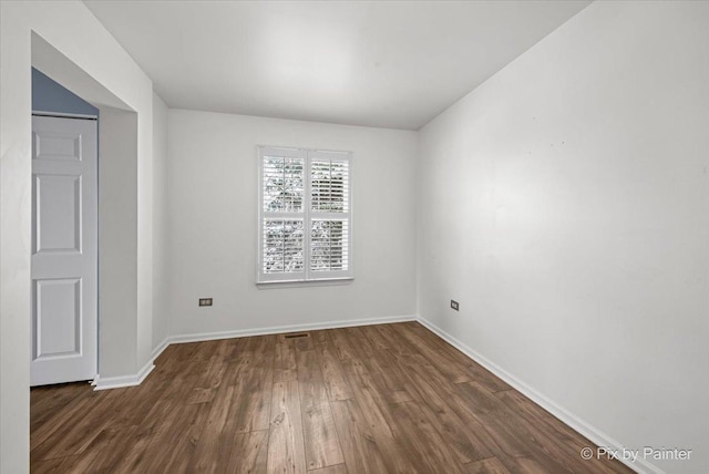empty room featuring visible vents, baseboards, and wood finished floors