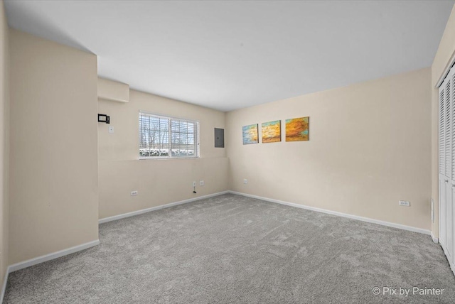 carpeted empty room featuring electric panel and baseboards