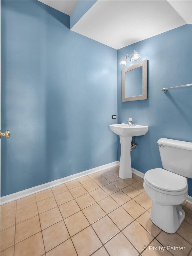 half bath with tile patterned flooring, toilet, and baseboards