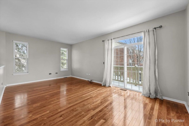 unfurnished room featuring visible vents, baseboards, and wood finished floors