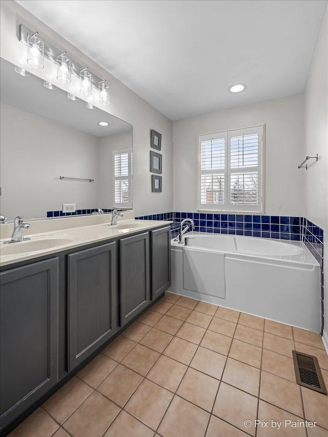 bathroom with tile patterned flooring, a bath, visible vents, and a sink