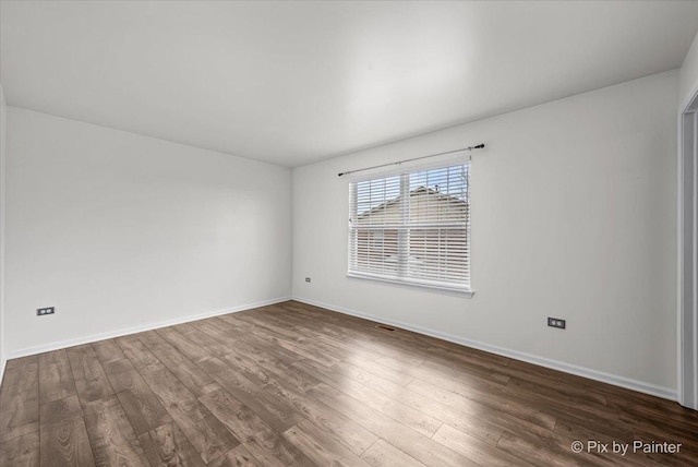 spare room with dark wood-type flooring and baseboards