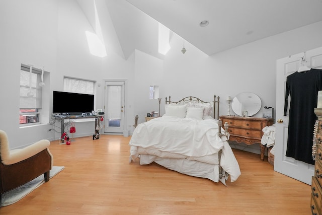 bedroom with light wood-type flooring and high vaulted ceiling