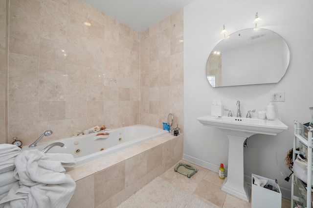 bathroom featuring tile patterned flooring, a tub with jets, and baseboards