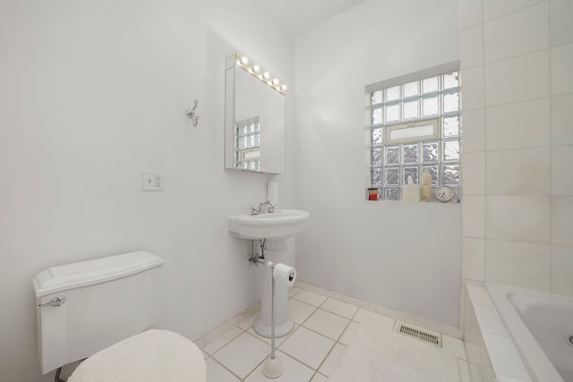 bathroom featuring tile patterned flooring, visible vents, toilet, and a relaxing tiled tub