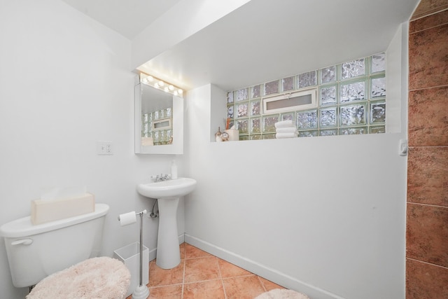 bathroom with baseboards, toilet, and tile patterned flooring