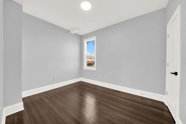 empty room with dark wood finished floors and baseboards