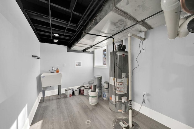 finished below grade area with baseboards, wood finished floors, and water heater