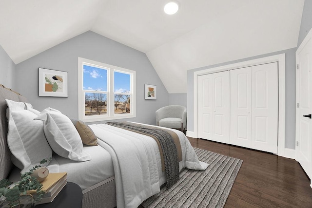 bedroom with a closet, wood finished floors, baseboards, and vaulted ceiling