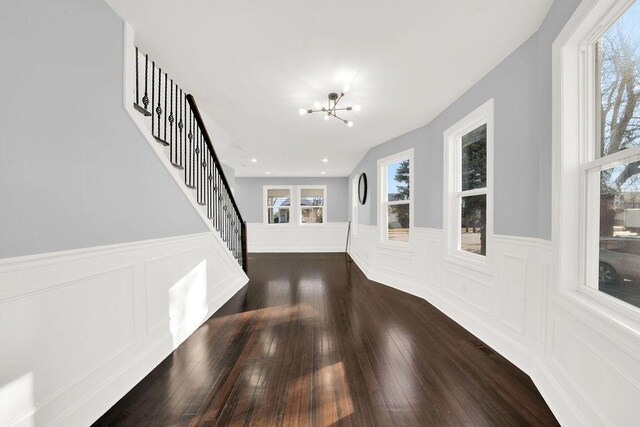 interior space with a notable chandelier, stairway, plenty of natural light, and dark wood-type flooring