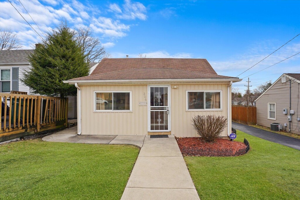 306 Johnson St, East Dundee, IL 60118 - view of front facade with board and batten siding, a shingled roof, a front lawn, and fence