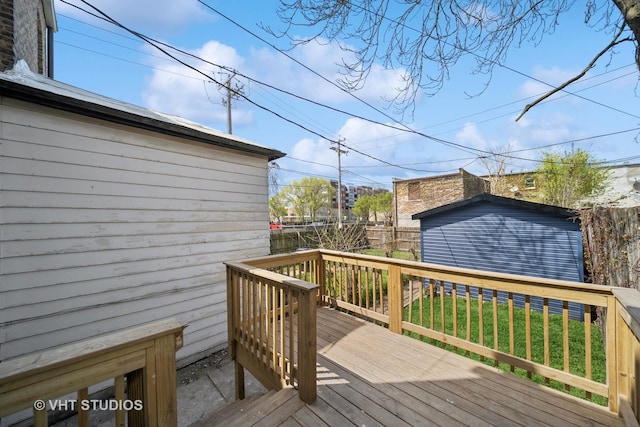 wooden terrace with a storage shed, an outbuilding, and fence