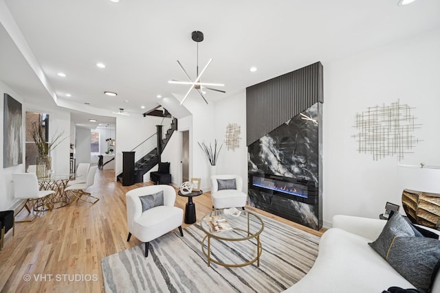 living area with a fireplace, recessed lighting, light wood-style floors, and stairway
