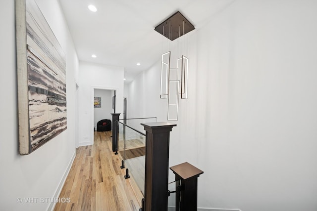 corridor with light wood-type flooring, an upstairs landing, baseboards, and recessed lighting