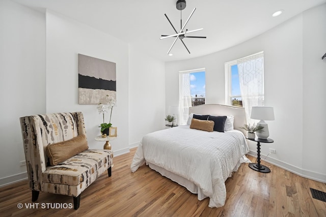bedroom with wood finished floors, baseboards, visible vents, recessed lighting, and a notable chandelier