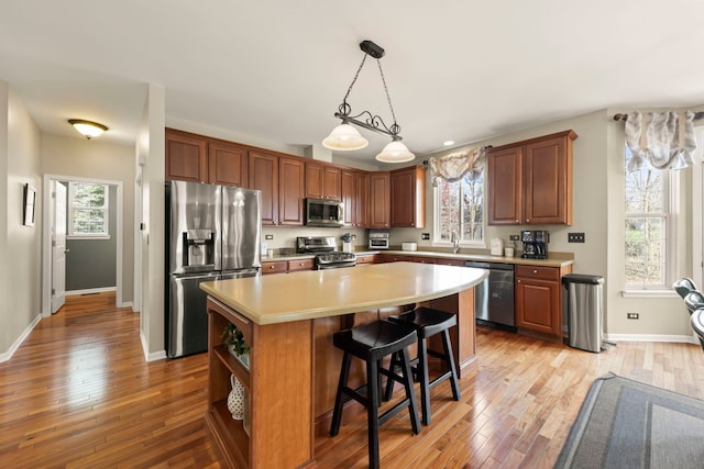 kitchen with light countertops, light wood-style flooring, a center island, and appliances with stainless steel finishes