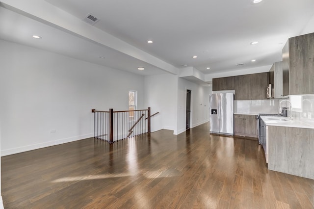 kitchen featuring backsplash, light countertops, appliances with stainless steel finishes, dark wood-style floors, and modern cabinets