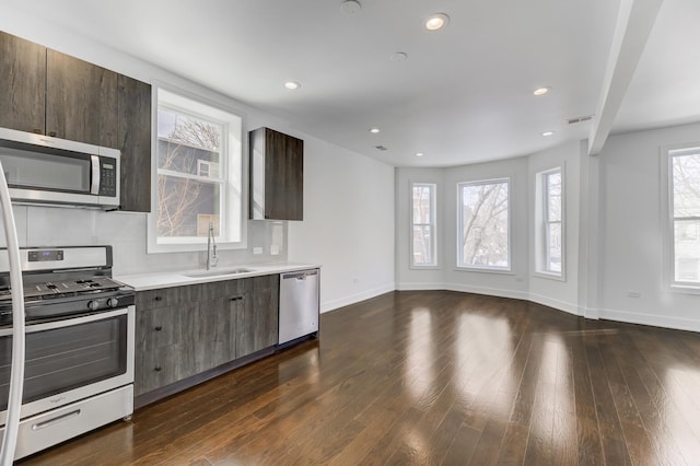 kitchen featuring dark wood finished floors, light countertops, appliances with stainless steel finishes, and a sink