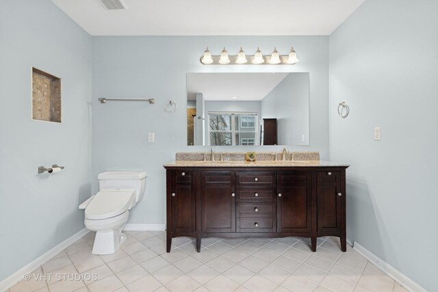bathroom featuring double vanity, toilet, baseboards, and a sink