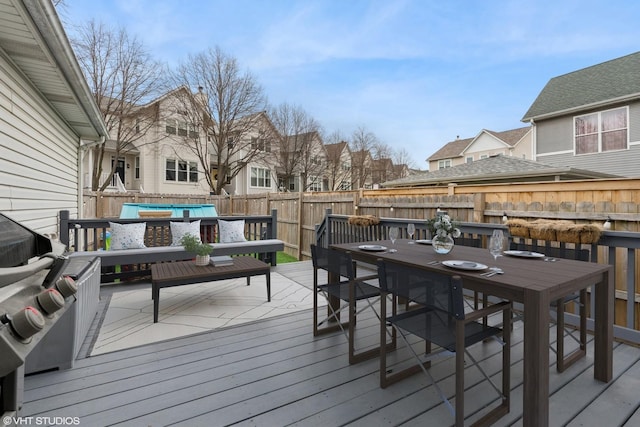 deck featuring area for grilling, a residential view, outdoor dining area, and a fenced backyard