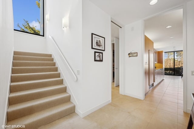stairway featuring baseboards, tile patterned flooring, and recessed lighting