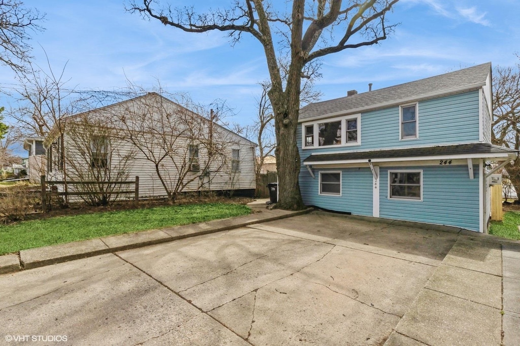 rear view of house featuring driveway and fence