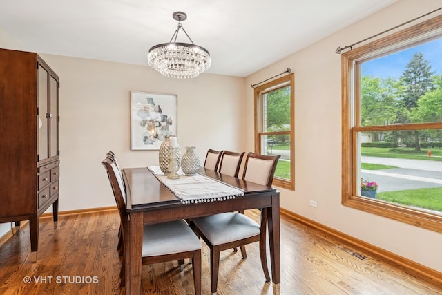 dining space with a chandelier, light wood-style floors, and baseboards