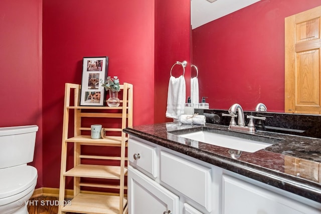 half bath with toilet, vanity, and wood finished floors