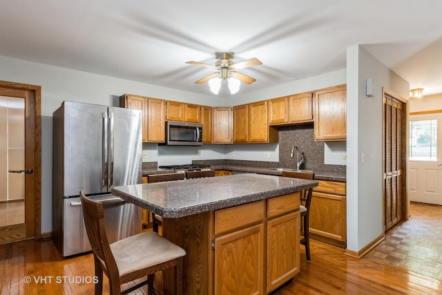 25W704 Jewell Rd, Wheaton, IL 60187 - kitchen featuring stainless steel appliances, a kitchen breakfast bar, wood finished floors, ceiling fan, and backsplash