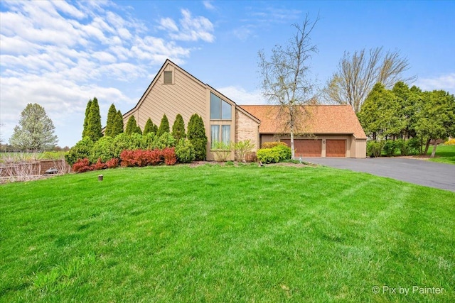 mid-century home featuring an attached garage, a front yard, and aphalt driveway