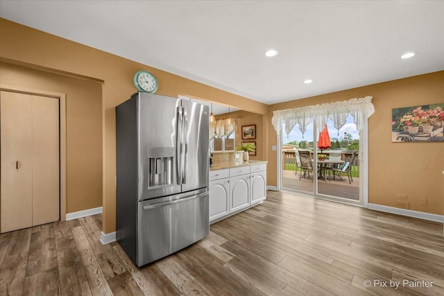 kitchen featuring baseboards, white cabinetry, wood finished floors, and stainless steel fridge with ice dispenser