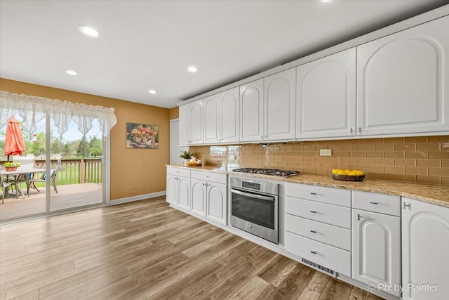 kitchen with baseboards, light wood finished floors, white cabinetry, and stainless steel appliances