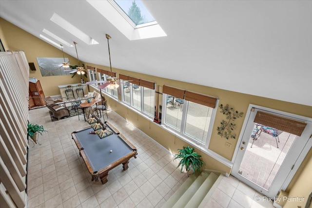 interior space featuring light tile patterned flooring, baseboards, billiards, vaulted ceiling with skylight, and a ceiling fan