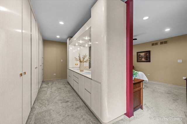hallway featuring light colored carpet, recessed lighting, and visible vents