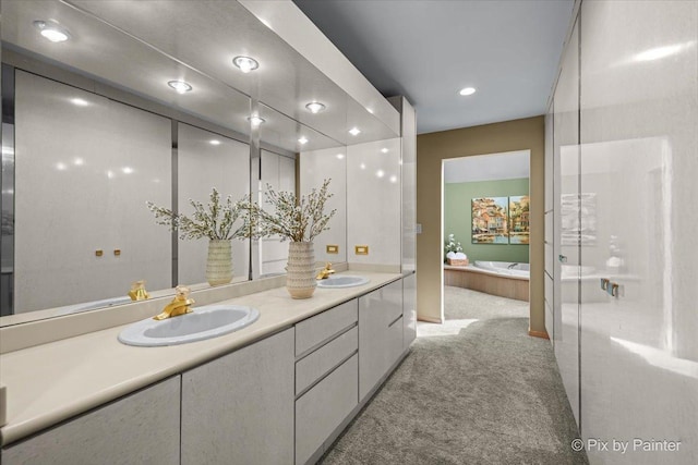 bathroom with double vanity, a sink, a bath, and recessed lighting