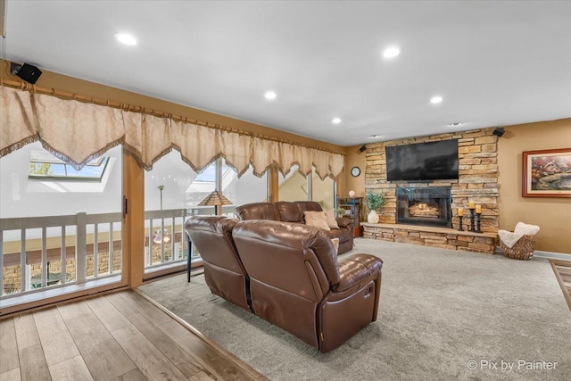 living area with recessed lighting, a stone fireplace, and wood finished floors