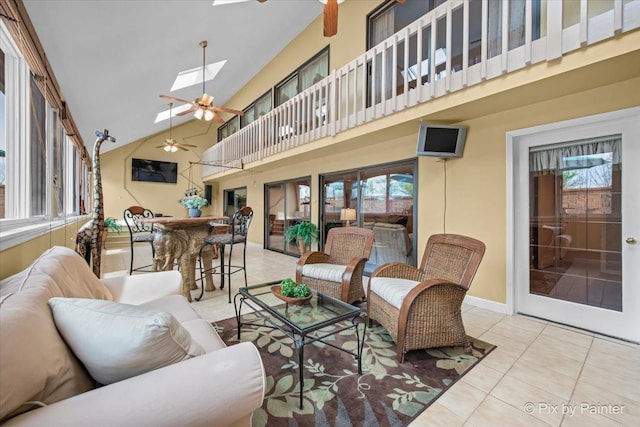 tiled living room with a ceiling fan, a skylight, a wealth of natural light, and high vaulted ceiling