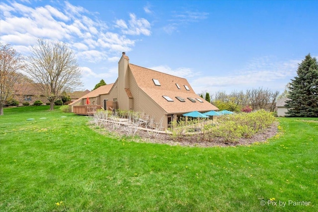 exterior space featuring a lawn, a deck, and a chimney