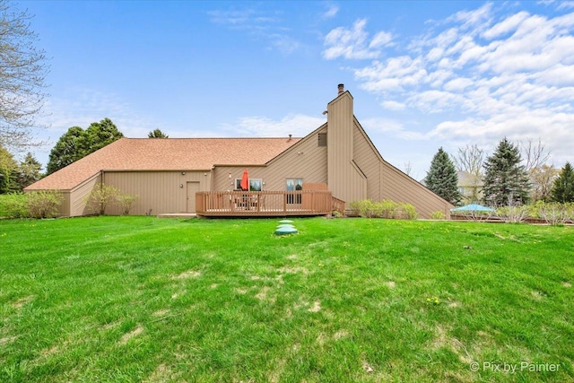 rear view of house featuring a wooden deck, a yard, and a chimney