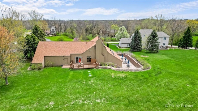 rear view of property featuring a lawn, a deck, a wooded view, and a chimney