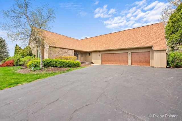 single story home with driveway, a shingled roof, and a garage
