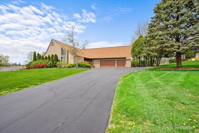 ranch-style house featuring driveway, a front lawn, and a garage