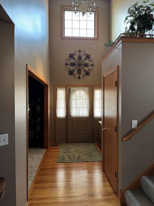 foyer entrance featuring an inviting chandelier, a high ceiling, stairs, and light wood-style floors