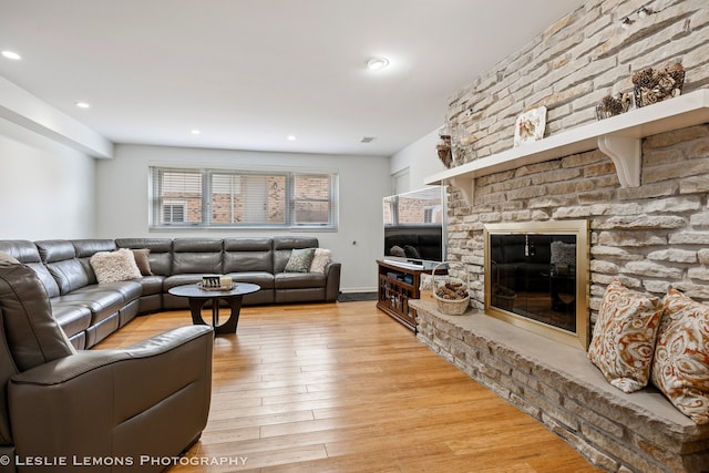 living room with recessed lighting, visible vents, a large fireplace, and light wood finished floors
