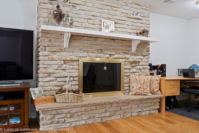 interior space with visible vents, a large fireplace, and wood finished floors