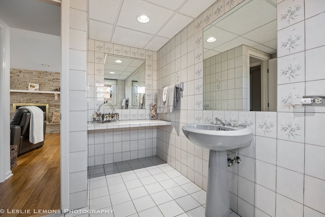 bathroom featuring a paneled ceiling, tile walls, and a fireplace