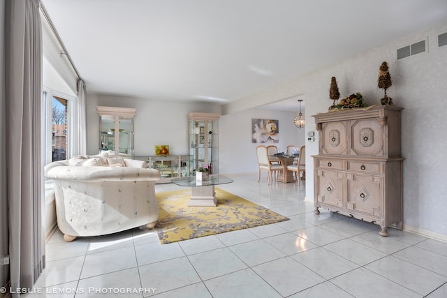 unfurnished living room featuring light tile patterned flooring, visible vents, and baseboards