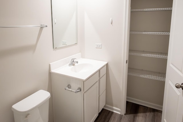 bathroom with baseboards, wood finished floors, toilet, and vanity