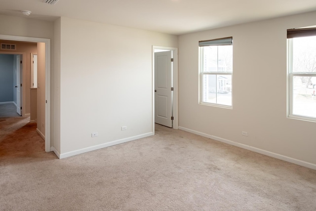 spare room with baseboards, carpet, a healthy amount of sunlight, and visible vents
